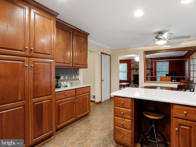 kitchen with ornamental molding, light stone counters, and ceiling fan