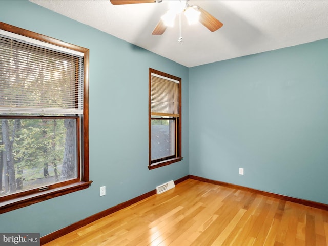 spare room featuring a textured ceiling, light wood-type flooring, and ceiling fan