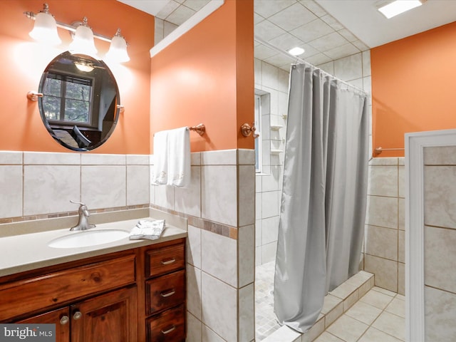 bathroom featuring tile patterned flooring, curtained shower, vanity, and tile walls