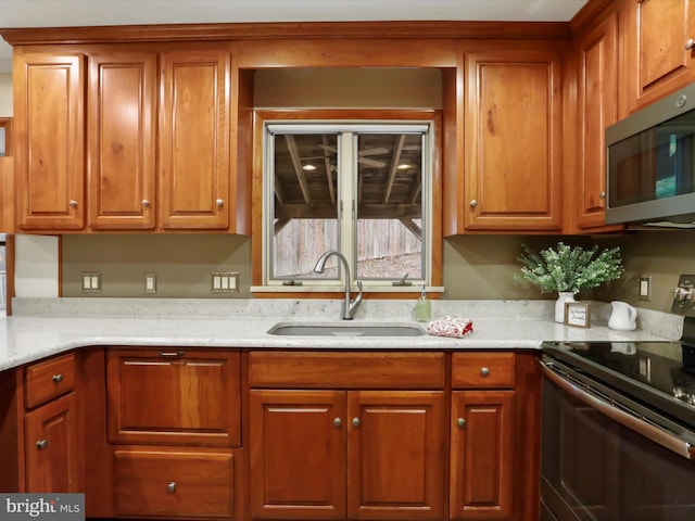 kitchen featuring black range with electric cooktop, light stone counters, and sink