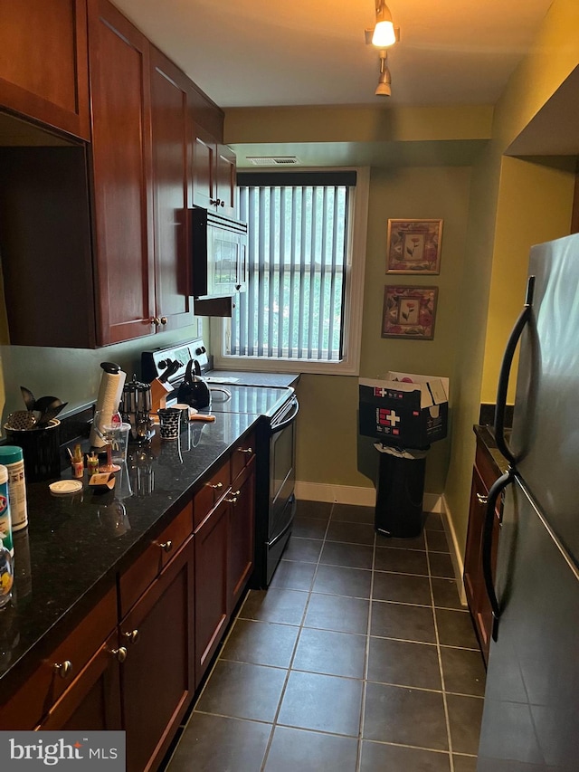 kitchen featuring dark stone countertops, appliances with stainless steel finishes, and dark tile patterned floors