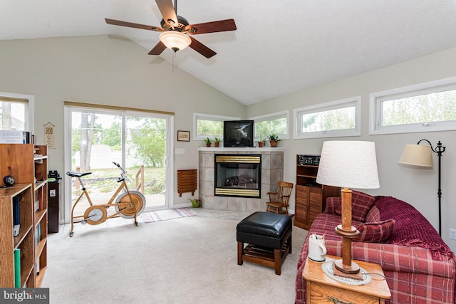 living room featuring carpet flooring, lofted ceiling, a tiled fireplace, and a healthy amount of sunlight