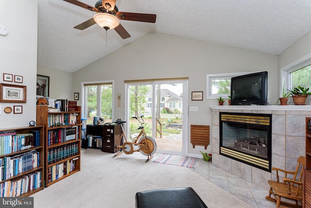 carpeted living room with a wealth of natural light, a tiled fireplace, and ceiling fan