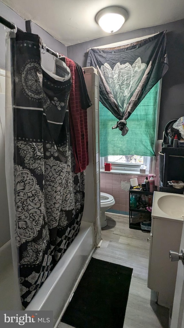 full bathroom featuring tile walls, vanity, shower / bath combination with curtain, hardwood / wood-style flooring, and toilet