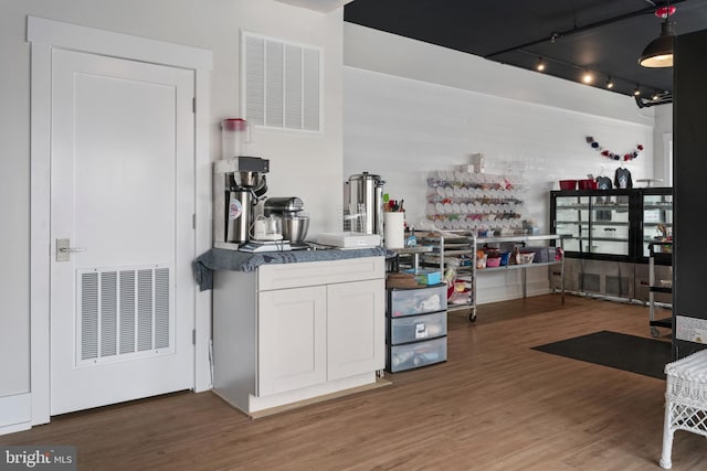 bar featuring rail lighting, white cabinetry, and dark wood-type flooring