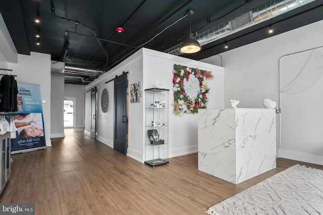 interior space with a barn door and hardwood / wood-style floors