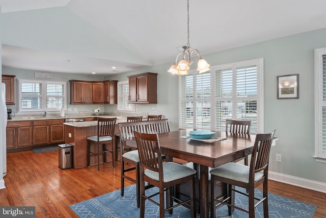 dining area with a notable chandelier, dark wood-type flooring, and vaulted ceiling