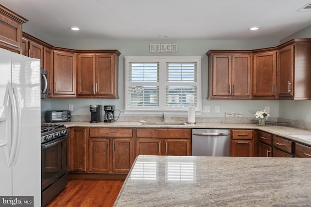 kitchen featuring light stone countertops, appliances with stainless steel finishes, dark hardwood / wood-style floors, and sink