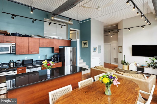 kitchen with stainless steel appliances, open floor plan, a towering ceiling, and rail lighting