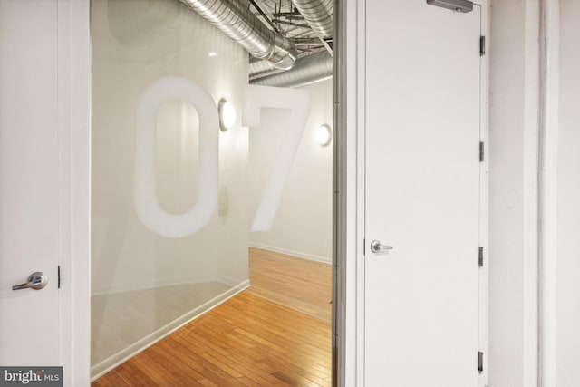 corridor with baseboards and hardwood / wood-style floors