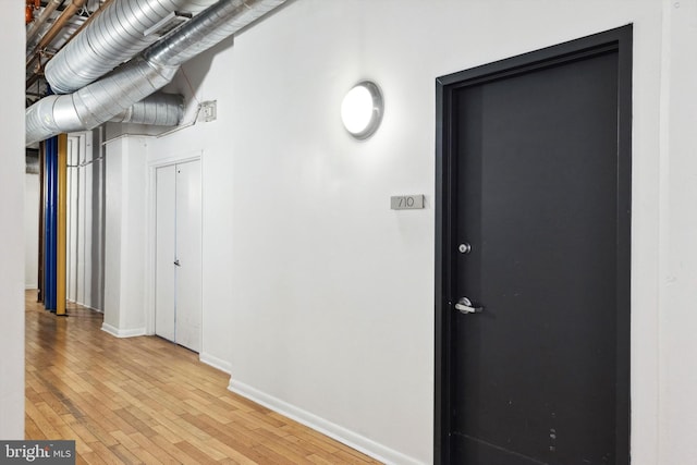 corridor featuring light wood-type flooring and baseboards