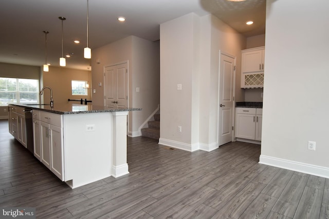 kitchen featuring dark hardwood / wood-style floors, sink, a center island with sink, and white cabinets