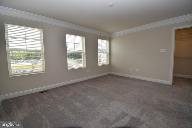 unfurnished room with ornamental molding and dark colored carpet