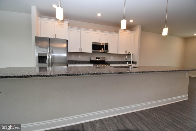 kitchen featuring white cabinets, dark hardwood / wood-style flooring, sink, pendant lighting, and stainless steel appliances