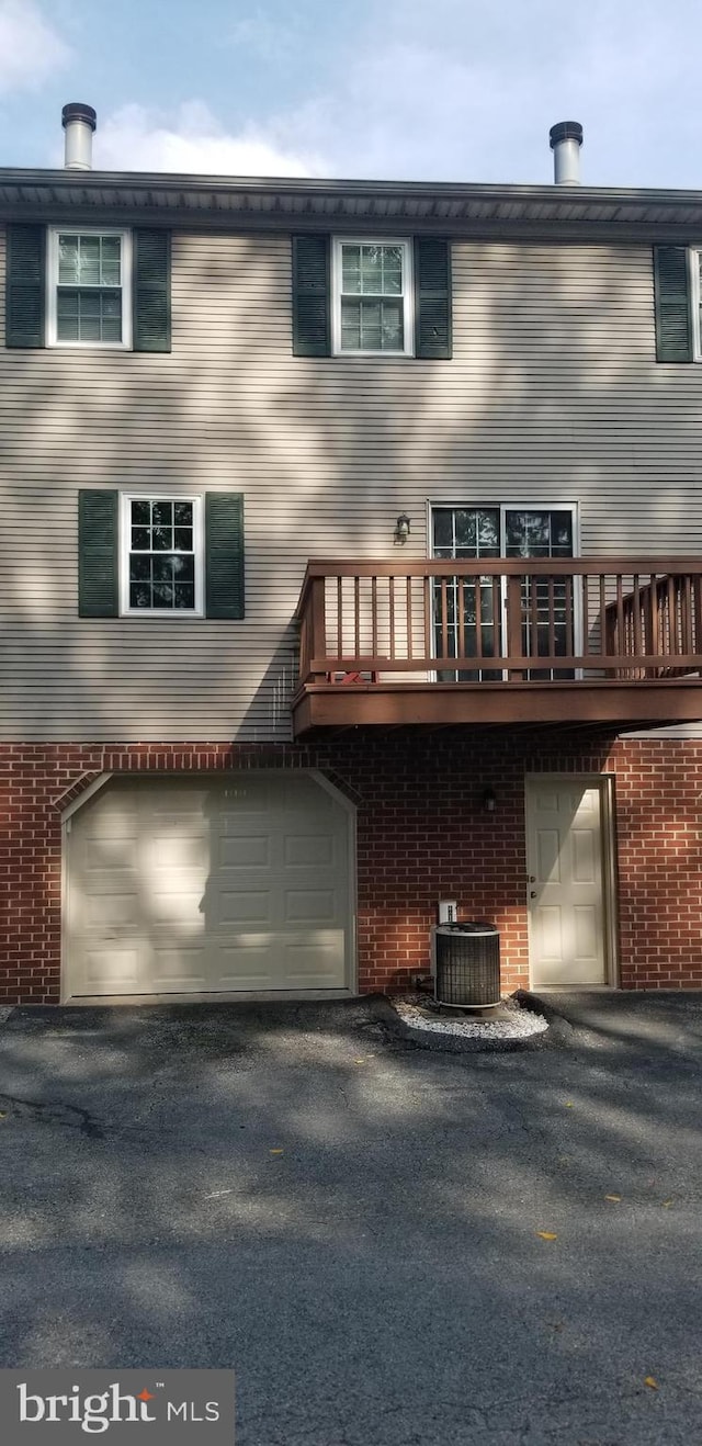 back of property featuring a garage, a wooden deck, and central air condition unit