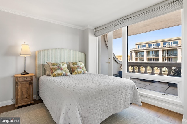 bedroom featuring baseboards, crown molding, and wood finished floors