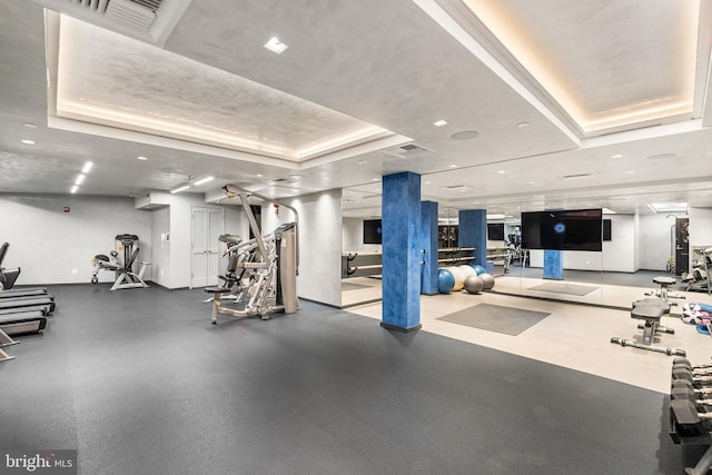 gym with a tray ceiling and visible vents