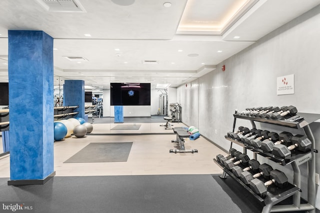 gym featuring visible vents, a raised ceiling, and recessed lighting