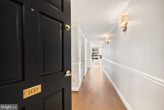 corridor with baseboards, light wood-style flooring, and crown molding