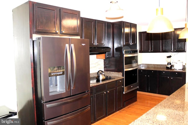 kitchen featuring ventilation hood, decorative light fixtures, light wood-type flooring, appliances with stainless steel finishes, and light stone countertops