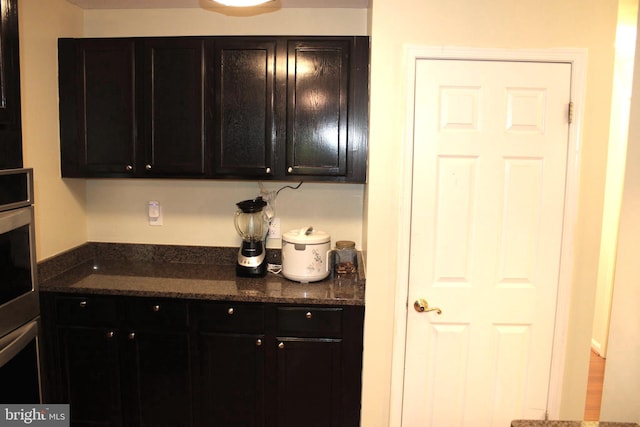 kitchen featuring stainless steel oven and dark stone counters