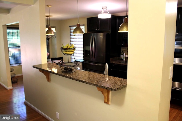 kitchen with dark hardwood / wood-style floors, refrigerator, dark stone counters, and decorative light fixtures