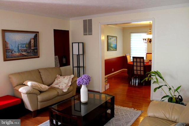 living room with crown molding, an inviting chandelier, and wood-type flooring