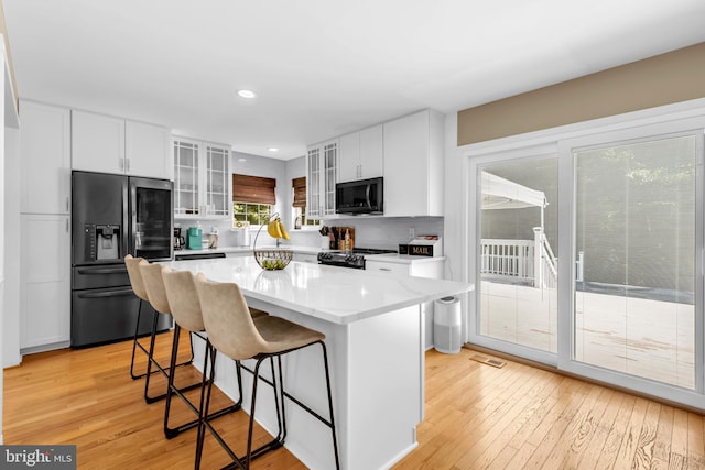 kitchen featuring light hardwood / wood-style flooring, refrigerator with ice dispenser, white cabinets, and a kitchen island