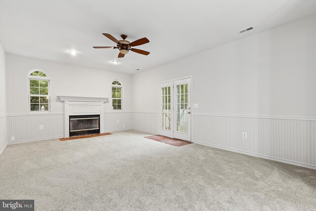 unfurnished living room with ceiling fan, light colored carpet, and french doors