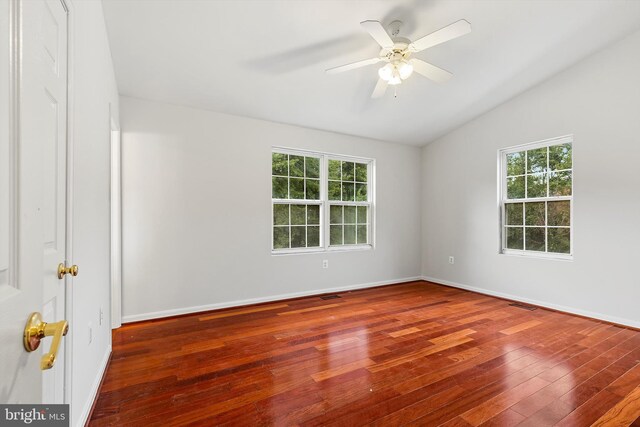 empty room with lofted ceiling, dark hardwood / wood-style flooring, ceiling fan, and a wealth of natural light