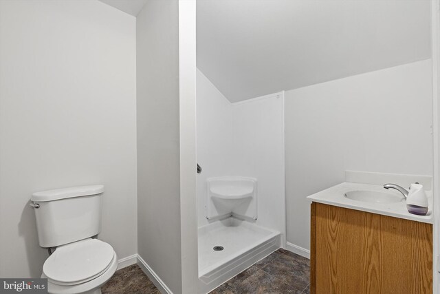 bathroom with walk in shower, lofted ceiling, vanity, and toilet