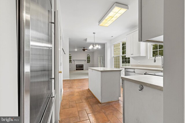 kitchen with hanging light fixtures, stainless steel fridge, white cabinetry, a kitchen island, and a chandelier