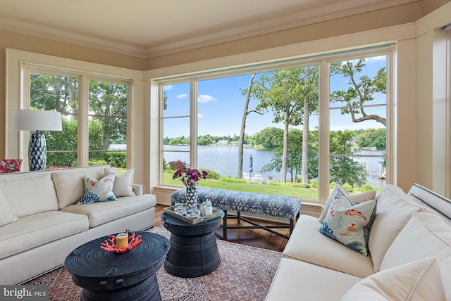 living room with hardwood / wood-style flooring, crown molding, a water view, and a healthy amount of sunlight