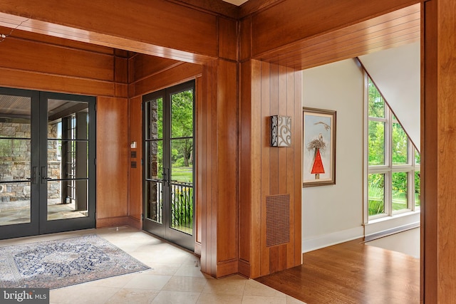 entrance foyer featuring wood walls, plenty of natural light, and french doors