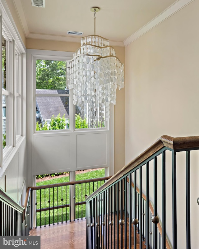 stairway featuring an inviting chandelier, ornamental molding, and hardwood / wood-style floors