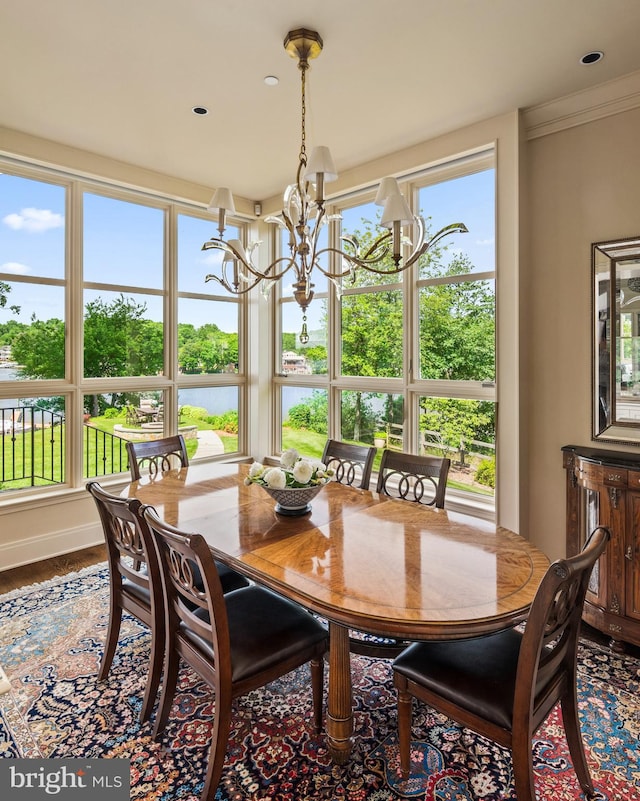 dining area with ornamental molding, an inviting chandelier, plenty of natural light, and hardwood / wood-style floors