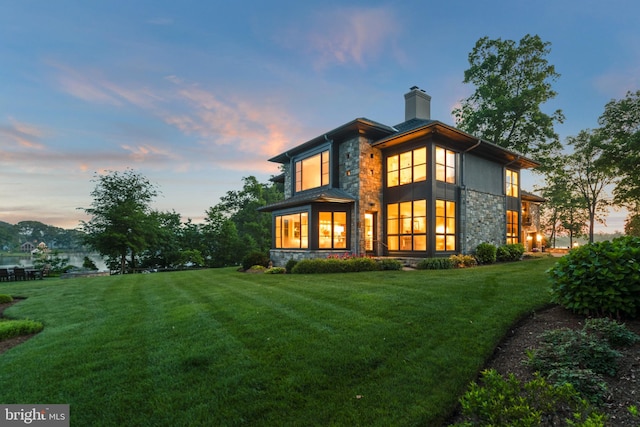 back house at dusk featuring a yard