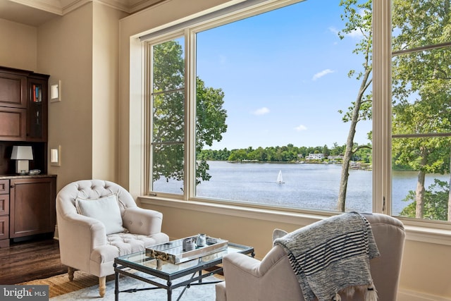 living area with a water view, ornamental molding, and dark hardwood / wood-style floors