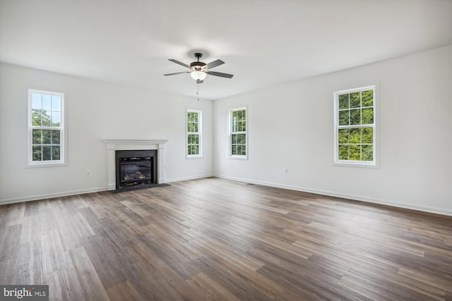 unfurnished living room featuring ceiling fan, plenty of natural light, and dark hardwood / wood-style floors