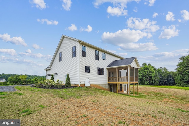 back of property with a sunroom, a lawn, and a wooden deck