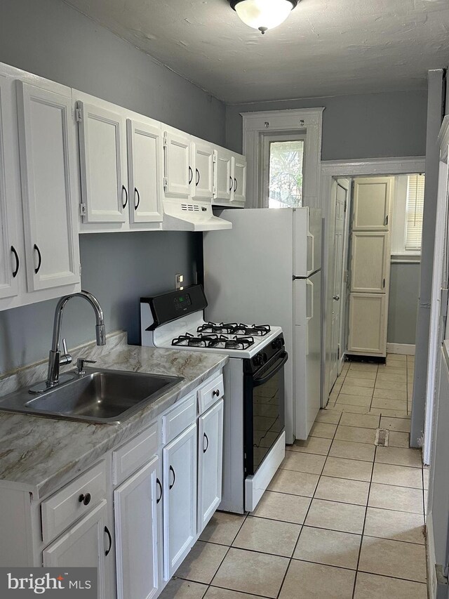 kitchen with white gas stove, white cabinetry, and sink