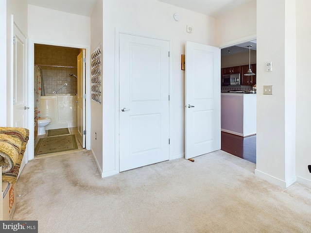 interior space featuring ensuite bath and light carpet