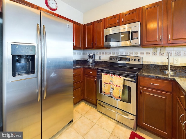 kitchen featuring backsplash, dark stone countertops, light tile patterned floors, and appliances with stainless steel finishes