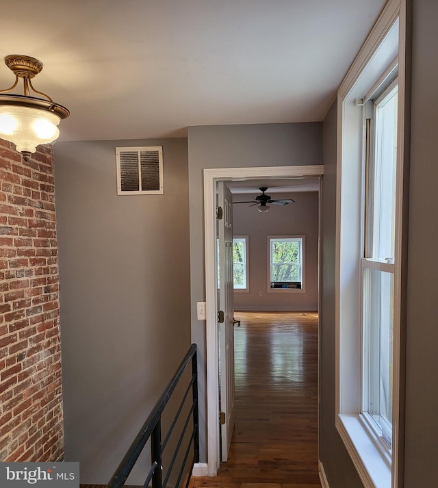 hallway featuring brick wall and dark hardwood / wood-style flooring