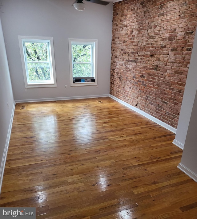 spare room with brick wall and dark hardwood / wood-style floors