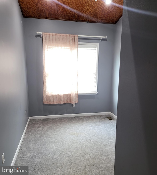 carpeted spare room with wood ceiling