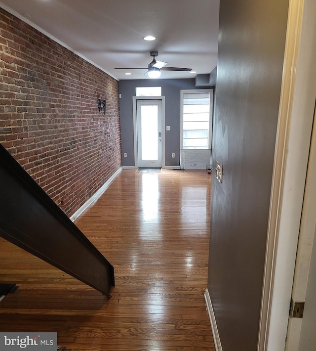 hallway featuring wood-type flooring and brick wall