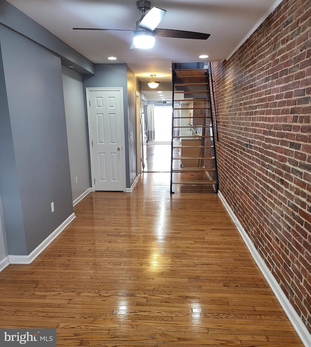 corridor with brick wall and hardwood / wood-style flooring