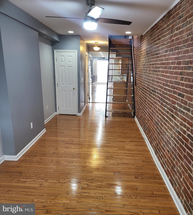 hall with brick wall and hardwood / wood-style floors