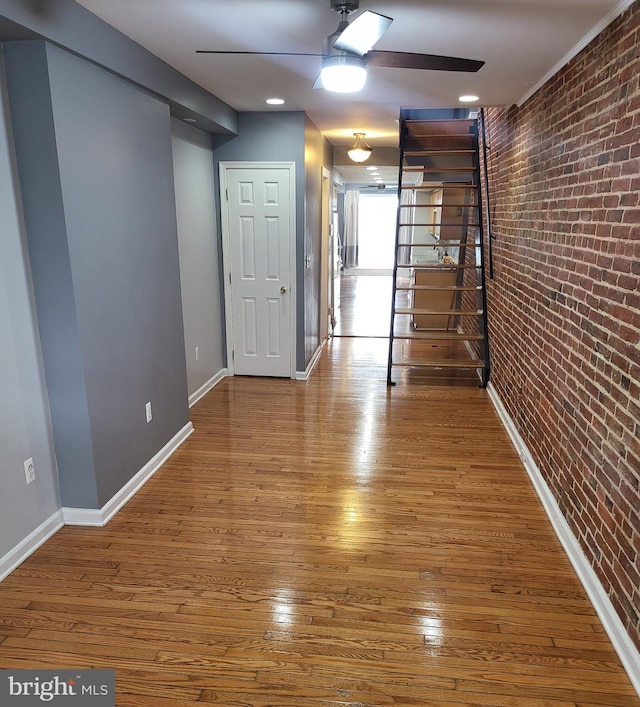 hallway with brick wall and hardwood / wood-style flooring